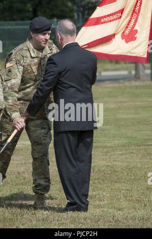 Ansbach, Germania -- Esercito degli Stati Uniti Garrison (USAG) Ansbach comandante uscente Col. Benjamin C. Jones passa i colori unità al sig. Michael D. Formica, installazione comando Gestione Regione Europa direttore durante la USAG Ansbach Modifica del comando cerimonia alla Caserma Barton parade campo, Ansbach, Germania, 18 luglio 2018. Foto Stock