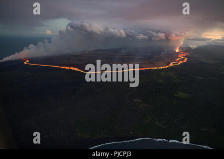 Un fiume di lava fluisce dalla fessura 8 di Hawaii vulcano Kilauea (a destra) attraverso la Puna inferiore per inserire l'oceano, rilasciando una nuvola di vapore acida. Foto Stock