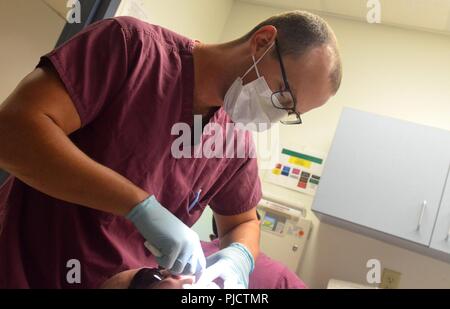 Il Jacksonville, Florida (24 luglio 2018) Lt. Cameron McMillin, un dentista a Naval Hospital Branch Health Clinic Jacksonville, conduce annualmente un esame dentale. McMillan, nativo di Orlando in Florida, dice "Ci prendiamo cura della warfighters e accertarsi che tutti gli organi di servizio sono pronti a distribuire o difendere la nostra libertà". La Marina Dental Corps celebra il suo 106ª compleanno il 22 agosto, 2018 e continua a contribuire a missioni umanitarie in tutto il mondo. Foto Stock