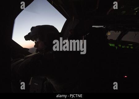 Un U.S. Air Force speciale missione aviatore assegnato alla quarantaseiesima Expeditionary squadrone di salvataggio si siede a bordo di un HH-60G Pavehawk durante una missione in Iraq, 18 luglio 2018. La missione primaria di HH-60G Pave Hawk elicottero è di condurre di giorno o di notte personale le operazioni di ripristino in ambienti ostili per recuperare personale isolato durante la guerra. Foto Stock