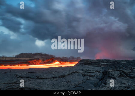 Incandescente fiume di lava calda scorre attraverso Kapoho, Hawaii dal vulcano Kilauea est Zona di rift verso l'oceano. Luccicante ondate di calore falsare la vista Foto Stock