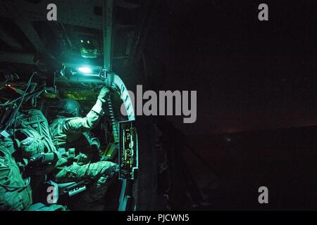 Un U.S. Air Force speciale missione aviatore assegnato alla quarantaseiesima Expeditionary squadrone di salvataggio si siede a bordo di un HH-60G Pavehawk durante una missione in Iraq, 18 luglio 2018. La missione primaria di HH-60G Pave Hawk elicottero è di condurre di giorno o di notte personale le operazioni di ripristino in ambienti ostili per recuperare personale isolato durante la guerra. Foto Stock