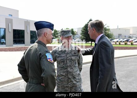 Gov. John Hickenlooper del Colorado, dice addio al Col. Troy Endicott, centro spazio 460th Wing Commander e Col. Brian Turner, estrema sinistra, centoquarantesimo Wing Commander, a seguito di una visita a Buckley Air Force Base in Colorado, luglio 17, 2018. Hickenlooper si è incontrato con il totale-force aviatori assegnato al Team Buckley e stato informato su Buckley AFB dell'ampia capacità di missione nonché l'impronta nella comunità locale. Foto Stock