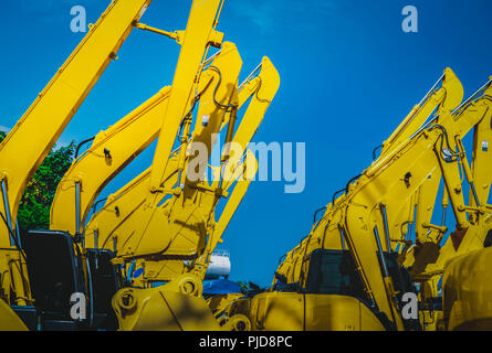 Giallo retroescavatore con pistone idraulico braccio contro il cielo blu e chiaro. Macchina pesante per lo scavo nel sito in costruzione. Macchine idrauliche. Enorme infrangere Foto Stock