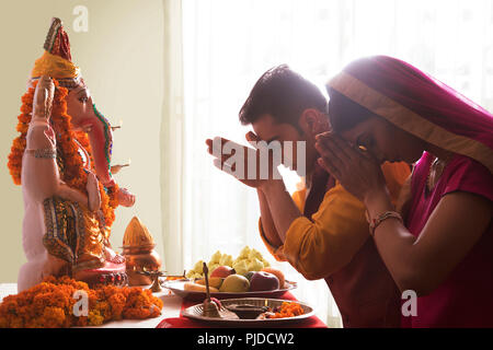 Il marito e la moglie a pregare con le mani giunte nella parte anteriore del Ganesha idolo in occasione del Ganesh Chaturthi Foto Stock
