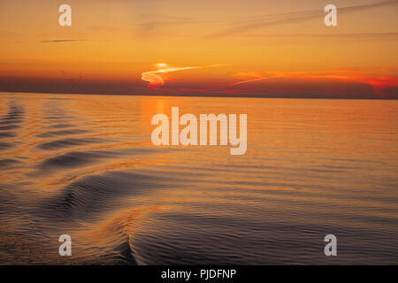 Tramonto sul Mar Baltico - Wake strappando oltre un eccezionalmente mare calmo. Foto Stock