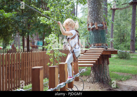 Bambina in marcia passa un ostacolo nella fune park. Foto Stock