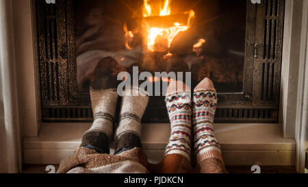 Primo piano immagine di piedi in calze di lana che giace accanto al caminetto Foto Stock
