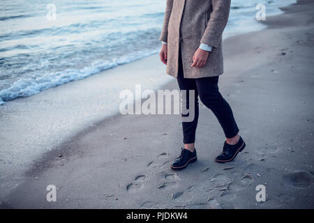 Giovane donna camminando sulla spiaggia, lasciando tracce nella sabbia bagnata, sezione bassa Foto Stock