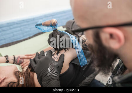 Tattooist disegno sul braccio del client Foto Stock