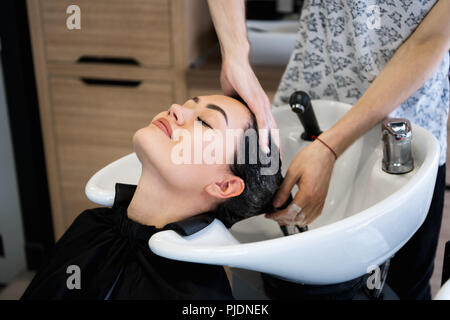 La bellezza e il concetto di persone - felice giovane donna con parrucchiere testa di lavaggio al parrucchiere Foto Stock