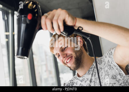 Parrucchiere maschio sorridente e parlare con un cliente mentre si effettua un nuovo taglio di capelli alla bella bruna giovane donna Foto Stock