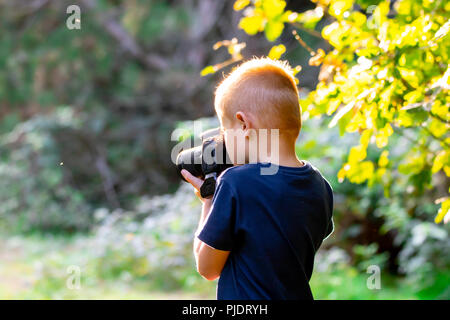 Ragazzo giovane learning fotografia con la sua prima DSLR nei boschi. Foto Stock