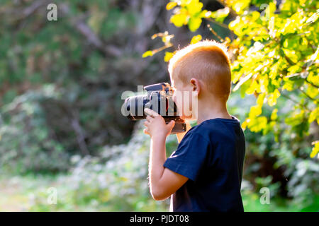 Ragazzo giovane learning fotografia con la sua prima DSLR nei boschi. Foto Stock