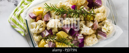 Banner di autunno ortaggi in un vetro vassoio da forno: cavolfiore, patate e cipolle rosse. sano cibo cotto in forno. Foto Stock