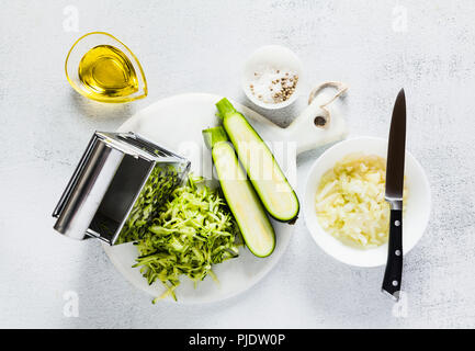 Ingredienti grezzi sul tavolo. le zucchine grattugiate e tritate finemente le cipolle. cibo sano. Foto Stock