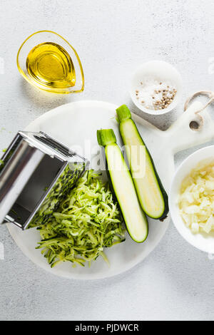 Ingredienti grezzi sul tavolo. le zucchine grattugiate e tritate finemente le cipolle. cibo sano. Foto Stock