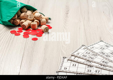 Carte da gioco, lotto in legno Barili con sacchetto verde e rosso di trucioli per un gioco nel lotto su cartone grigio. Gioco di bordo lotto Foto Stock