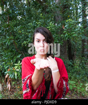 Giovani hippie bella bruna donna con lunga treccia di capelli bianchi con il trucco tribale inviando un bacio accanto a un albero Foto Stock