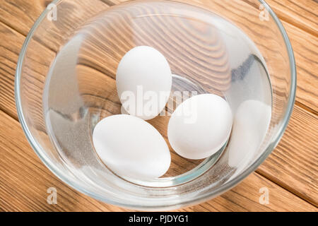 Tre uova di pollo in acqua. Controllo Freschezza Foto Stock