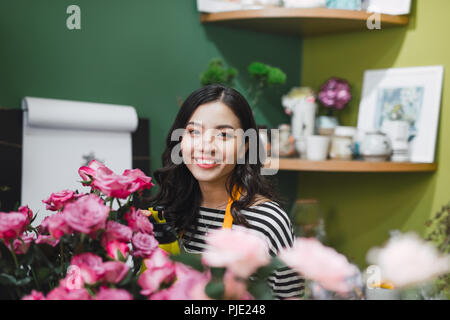Carino concentrata giovane femmina fioraio a lavorare nel negozio di fiori Foto Stock