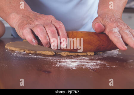 Le donne della nonna le mani stendete la pasta con un vintage mattarello sul tavolo Foto Stock