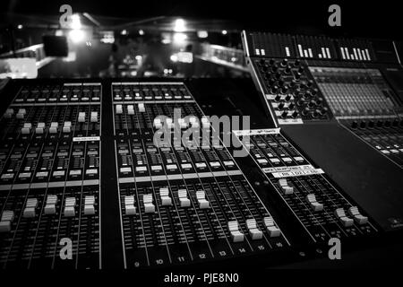 Ampia vista di Audio Professionale Console di miscelazione con l'artista esegue in background distanti, monocromatica in bianco e nero style Foto Stock