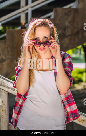 Tanga alla moda ragazza con occhiali da sole in piedi su scale, urban concept della gioventù Foto Stock