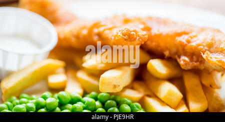 Cibo inglese tradizionale come pesce e patatine fritte con piselli verdi servita nel pub o ristorante Foto Stock
