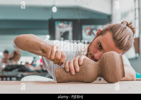 Giovane artista della ceramica lavorando sulla sua pentola di creta in un atelier Foto Stock