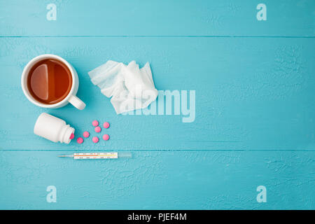 Termometro, compresse e tè su uno sfondo blu Foto Stock