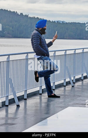 Passeggero in chalm con telefono sul ponte, traghetto, Vancouver, Victoria, Canada Foto Stock