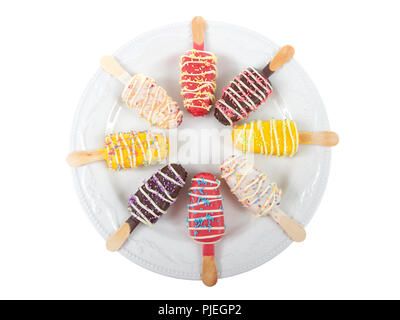 Più caramelle colorate spogliato ghiaccioli cake pops con spruzza sulla parte superiore su un bianco piastra di porcellana isolati su sfondo bianco. Divertimento piatti per le feste Foto Stock