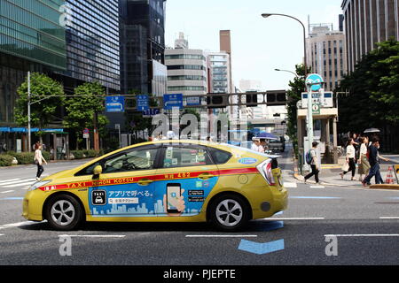 Una Toyota Prius ibrida con taxi (azionato da Nihon Katsu) attende in corrispondenza di una giunzione di Nihonbashi in Tokyo centrale come persone di attraversare la strada. (Giugno 2018) Foto Stock