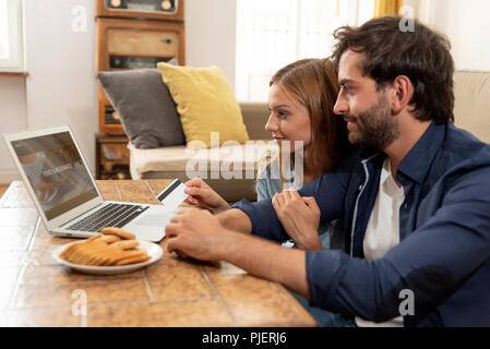 Coppia giovane facendo shopping online in internet e utilizzando una carta di credito Foto Stock