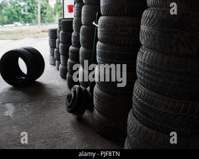 Auto Usate di pneumatici accatastati in pile a junkyard. Ruote vecchio riciclaggio e concetto di utilizzo. Foto Stock