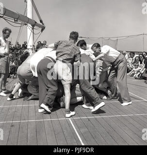 Degli anni Cinquanta, storici mid-oceano su una unione-castello steamship guidato per la Cape in Sud Africa, alcuni appassionati passeggeri maschi di giocare una partita di rugby di coperta e formare un scrum attorno ad una valigia. Foto Stock