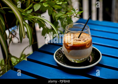 Caffè ghiacciato latte sul tavolo blu in estate Foto Stock