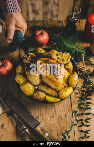 L'uomo messo pronto il natale il pollo nella padella sul tavolo. Pronto a mangiare e a servire. Cena di Natale concept Foto Stock