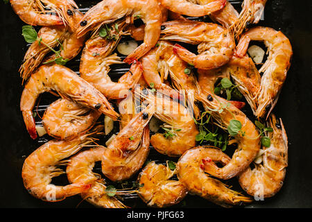 Gustoso e succulento arrosto di gamberi con spezie sul pan su sfondo nero. Vista dall'alto. Primo piano. Foto Stock