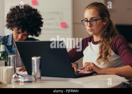 Startup business persone che lavorano in piccoli uffici coworking space. La donna caucasica lavorando sul computer portatile. Foto Stock