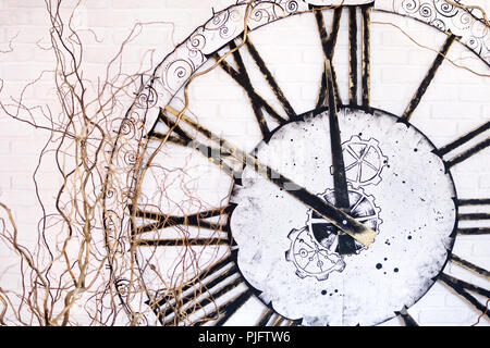 Sulla parete di un grande orologio con numeri romani che mostra a dieci minuti a dodici Foto Stock