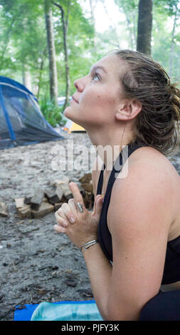 Giovane donna meditando con Kali mani mudra yoga pongono in campeggio nella foresta Foto Stock