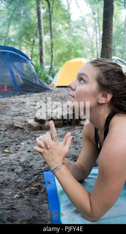 Giovane donna meditando con Kali mani mudra yoga pongono in campeggio nella foresta Foto Stock