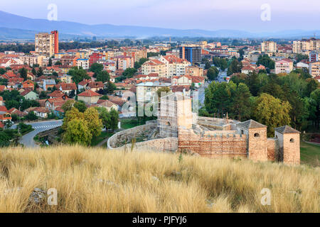 Ora blu cityscape, prima i colori autunnali degli alberi, asciutto erba in primo piano e la città antica fortezza in ricostruzione Foto Stock