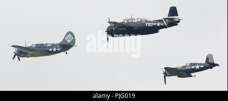 II Guerra Mondiale US Navy aeromobili battenti in formazione leader Curtiss SB2C-5 Helldiver, Grumman TBM-3E Avenger e Vought FG-1D Corsair a Thunder su Mic Foto Stock