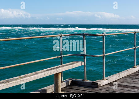 Un sedile unico sul Port Noarlunga Jetty che guarda al mare mosso e Reef in Sud Australia il 6 settembre 2018 Foto Stock