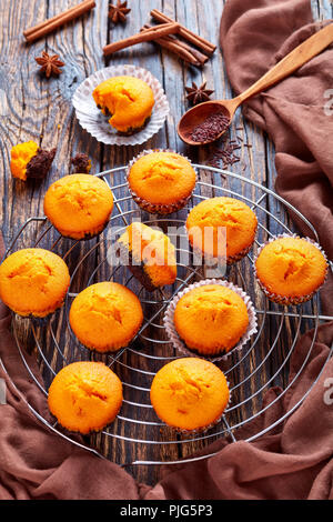 Appena sfornato dolci deliziosi muffin di zucca su un tondo in acciaio inox torta Raffreddamento per rack su una tavola in legno rustico, deliziosi dessert autunnale per HAL Foto Stock