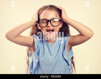 Rabbia giovane studiare kid ragazza in bicchieri forte urlando selvaggio con bocca aperta e tenendo la testa con le mani. Tonica closeup ritratto Foto Stock