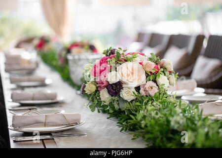 Ordinatamente intrecciati in un tubo sala da pranzo igienico decorate con un rametto di pistacchio. Banchetti per matrimoni o cene di gala. Il tavolo e sedie per gli ospiti, Servita con posateria e stoviglie. party sulla terrazza Foto Stock